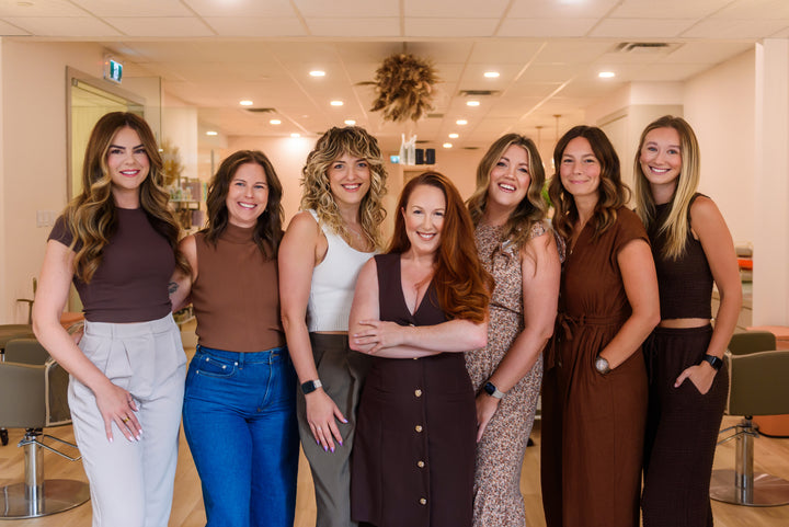 Group of seven women posing together in a salon