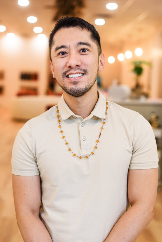 Man wearing a beige polo shirt with a blurred indoor background