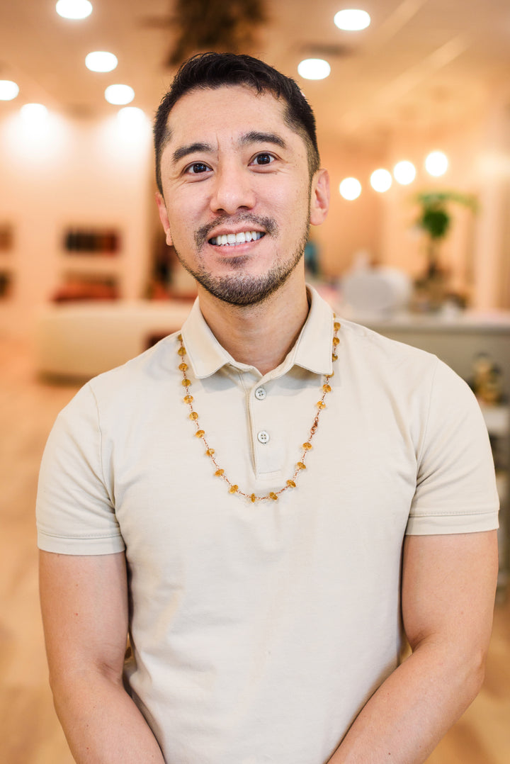 Man wearing a beige polo shirt with a blurred indoor background